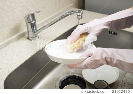 Hands of a housekeeper woman washing dishes with a sponge Hands of a housekeeper woman washing dishes with a sponge 81952420