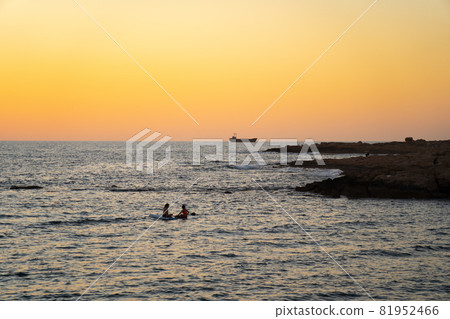 Two women sharing paddle board at sunset on calm waters in mediterranean sea in cyprus. Two girls on paddling on SUP. Silhuette in the distance. Water sport, sup surfing, surfboard or paddle boarder Two women sharing paddle board at sunset on calm waters in mediterranean sea in cyprus. Two girls on paddling on SUP. Silhuette in the distance. Water sport, sup surfing, surfboard or paddle boarder 81952466