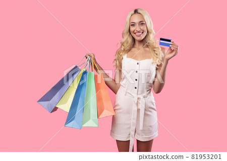 Happy woman holding credit card carrying shopping bags 81953201