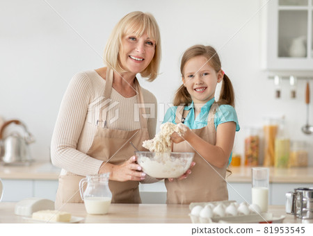 Happy senior lady and her granddaughter preparing dough 81953545