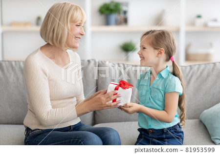Little girl greeting mature lady giving box Little girl greeting mature lady giving box 81953599