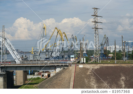 The loose abutment of the railway bridge against the background of harbor cranes. The loose abutment of the railway bridge against the background of harbor cranes. 81957368