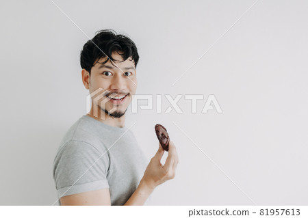 Happy man holding a chocolate cookie isolated on white background. Happy man holding a chocolate cookie isolated on white background. 81957613