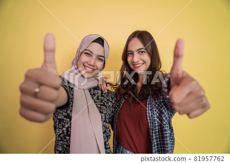 close up of faces of two smiling women looking at camera with thumbs up gesture 81957762