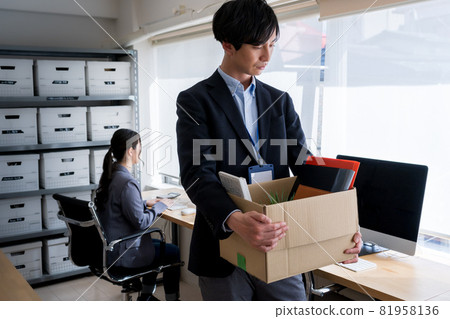 A mid-career male employee who is dismissed and leaves the company with a cardboard box containing personal belongings 81958136