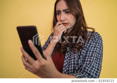 close up of asian woman looking at screen while using a smartphone with worried expression close up of asian woman looking at screen while using a smartphone with worried expression 81958515