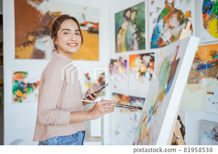 female artist painting hold phone while working female artist painting hold phone while working 81958538