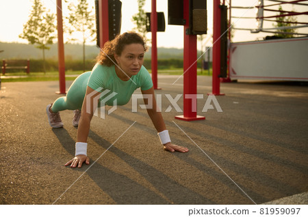 Young mixed race, African American woman athlete working out outdoor, doing push-ups on sportsground in summer. Healthy active lifestyle and fitness concept 81959097