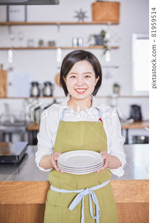 一個穿著圍裙的年輕女子站在廚房裡的盤子裡 一個穿著圍裙的年輕女子站在廚房裡的盤子裡 81959514