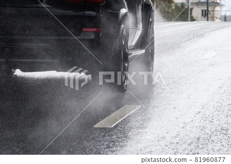 rain water splash flow from wheels of black car moving fast in daylight city with selective focus rain water splash flow from wheels of black car moving fast in daylight city with selective focus 81960877