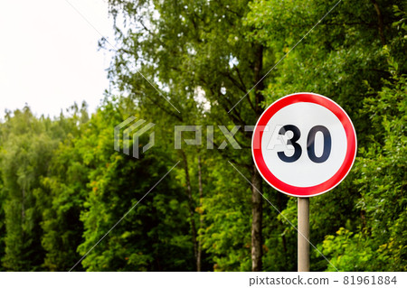 Road sign speed limit 30 kilometers per hour on green forest background with selective focus 81961884