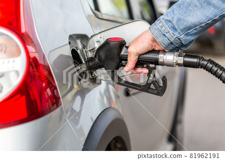 hand in jeans jacket refueling gray metallic car on gas station - closeup with selective focus hand in jeans jacket refueling gray metallic car on gas station - closeup with selective focus 81962191