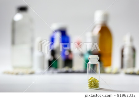 Small glass bottle with yellow gloss tablets on blurred meds background with selective focus Small glass bottle with yellow gloss tablets on blurred meds background with selective focus 81962332