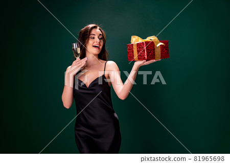 woman in black dress holds the gift red box and glass of champagne. Party time. Holiday concept woman in black dress holds the gift red box and glass of champagne. Party time. Holiday concept 81965698