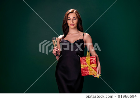woman in black dress holds the gift red box and glass of champagne. Party time. Holiday concept 81966694