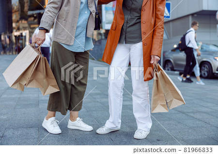 Pair of senior ladies holds shopping bags standing on modern city street Pair of senior ladies holds shopping bags standing on modern city street 81966833