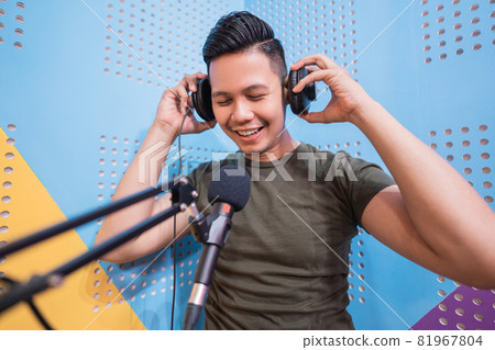 happy asian man is recording a podcast in his studio 81967804