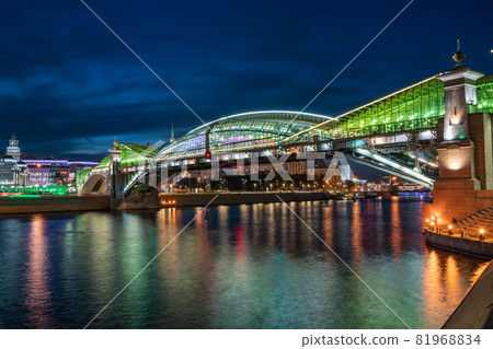 View of the colorful Bogdan Khmelnitsky bridge illuminated at night reflecting in the Moskova river. Moscow Kiyevsky railway station at night. Moscow, Russia View of the colorful Bogdan Khmelnitsky bridge illuminated at night reflecting in the Moskova river. Moscow Kiyevsky railway station at night. Moscow, Russia 81968834