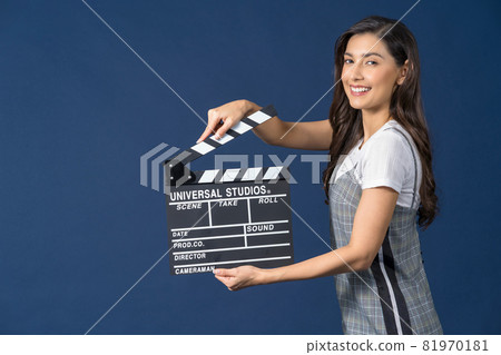 Happy young Asian woman holding movie clapperboard on studio setup film on blue color background, broadcast and producer, cinema and movie cut concept 81970181