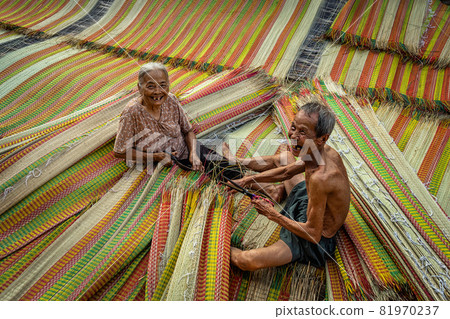 Top view of old Vietnamese lover craftsman making the traditional vietnam mats with happiness action in the old traditional village at dinh yen, dong thap, vietnam, tradition artist concept 81970237
