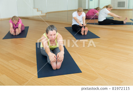 Ladies are doing seating forward bend Ladies are doing seating forward bend 81972115