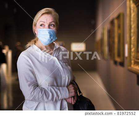 Closeup on mature female in face mask visiting museum Closeup on mature female in face mask visiting museum 81972552
