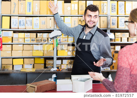 seller helping female client to choose door hinges in houseware shop 81972557