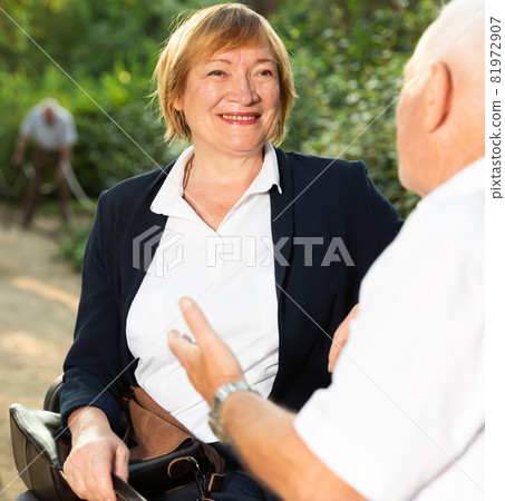 Elderly couple talking on bench Elderly couple talking on bench 81972907
