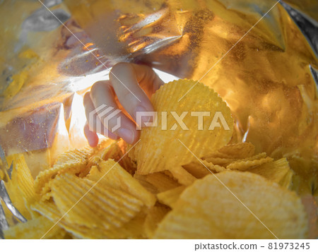 Hand taking potato chips inside the bag Hand taking potato chips inside the bag 81973245