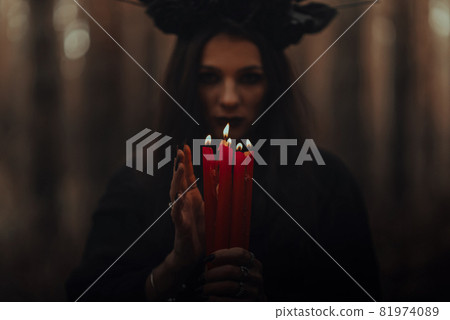 frightening witch performs an occult ritual with candles 81974089