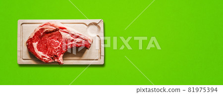 Beef prime rib and wooden cutting board isolated on green background. Horizontal banner 81975394