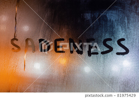 the word sadeness written by finger on night wet glass with blurred lights in background the word sadeness written by finger on night wet glass with blurred lights in background 81975429