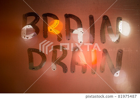 the words brain drain written on night wet window glass close-up with blurred background in orange colors the words brain drain written on night wet window glass close-up with blurred background in orange colors 81975487