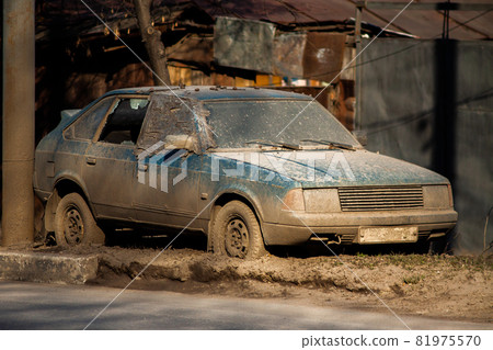 Old dirty abandoned car on sideroad with thick layer of mud and broken window at daylight. Old dirty abandoned car on sideroad with thick layer of mud and broken window at daylight. 81975570
