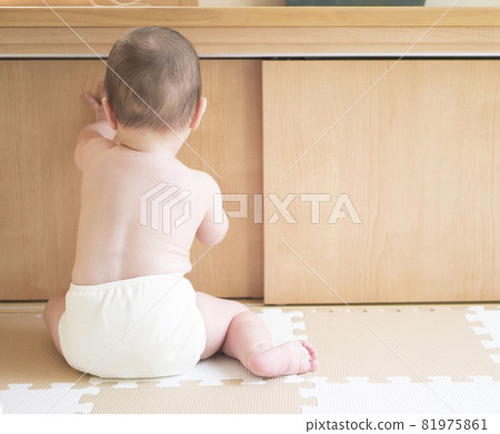 嬰兒赤身裸體坐著,穿著尿布的後視圖 嬰兒赤身裸體坐著,穿著尿布的後視圖 81975861