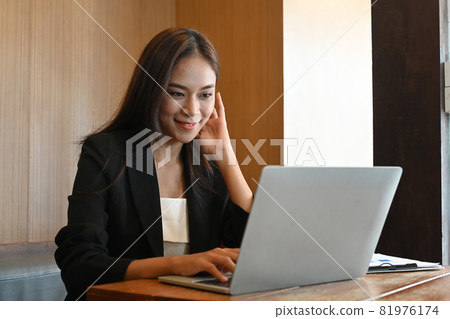 Attractive businesswoman in suit working with laptop computer at her office room. Attractive businesswoman in suit working with laptop computer at her office room. 81976174