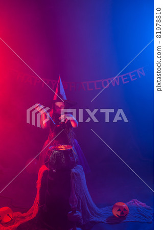Child girl witch preparing a potion in the cauldron at halloween holidays. Child girl witch preparing a potion in the cauldron at halloween holidays. 81978810