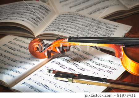 Violin with bow resting on musical score 81979431
