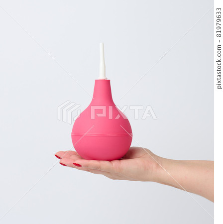 hand holds a pink rubber enema on a white background hand holds a pink rubber enema on a white background 81979633