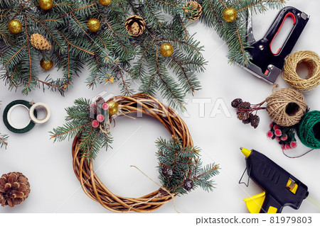 Creative christmas diy. Woman making handmade xmas wreath. Home leisure, tools, trinkets and details for holiday decorations on white table background. Top view Creative christmas diy. Woman making handmade xmas wreath. Home leisure, tools, trinkets and details for holiday decorations on white table background. Top view 81979803
