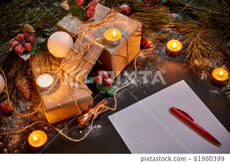 Christmas gifts, burning candles and notebook lying near green spruce branch on black background top view. Space for text Christmas gifts, burning candles and notebook lying near green spruce branch on black background top view. Space for text 81980399