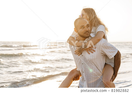 Young happy couple on seashore enjoying the sea Young happy couple on seashore enjoying the sea 81982882
