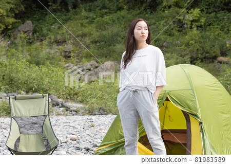 Girl standing next to a tent at a camp 81983589