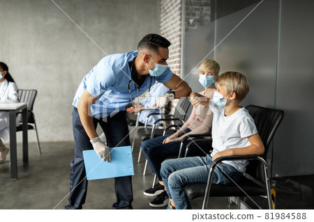 Friendly doctor talking to little boy before vaccination Friendly doctor talking to little boy before vaccination 81984588