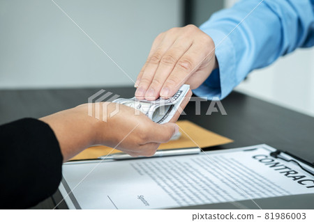 Close up of man employee receiving bribe dollars in his hands from businessman after signing the contract 81986003