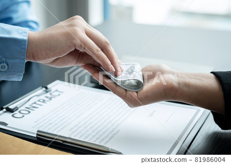 Close up of man employee receiving bribe dollars in his hands from businessman after signing the contract Close up of man employee receiving bribe dollars in his hands from businessman after signing the contract 81986004