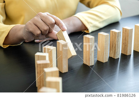 Risk and Strategy in Business, Image of hand stopping falling collapse wooden block dominoes effect from continuous toppled block, prevention and development to stability 81986126
