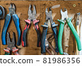 Set of pliers and nippers tools hanging on a wall 81986356