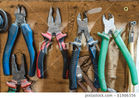 Set of pliers and nippers tools hanging on a wall Set of pliers and nippers tools hanging on a wall 81986356
