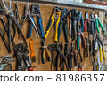 Set of pliers and nippers tools hanging on a wall 81986357